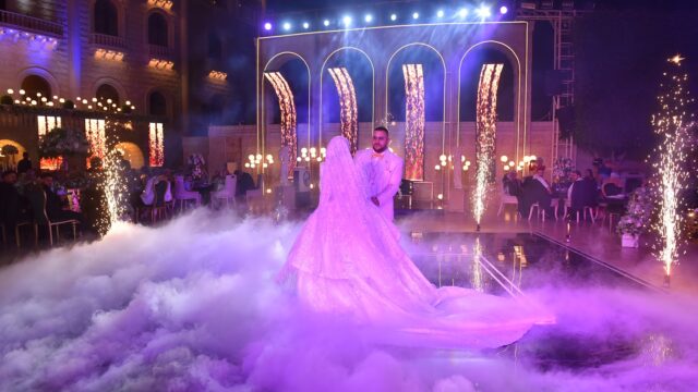 A man and woman, gracefully choreographed, enchantingly dance in front of a stage enveloped in ethereal smoke at Jardin Du Rêve - Le Rêve.