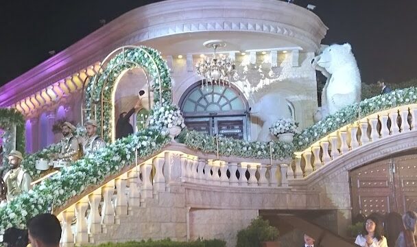 In the Jardin Du Rêve - Le Rêve, a building with a decorated staircase stands grandly, mesmerizing visitors as people walk around in awe.