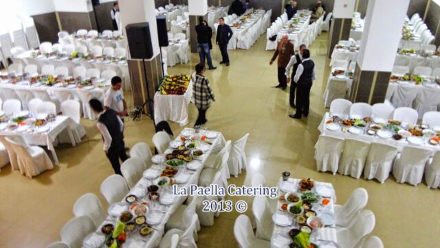 La Paella Catering provides a group of people in a room with tables and chairs.
