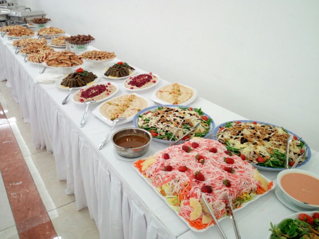A long table with plates of food on it is beautifully set up by La Paella Catering.