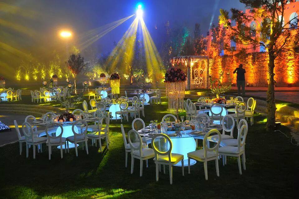 A group of tables and chairs in a garden, complemented by Larissa Catering.