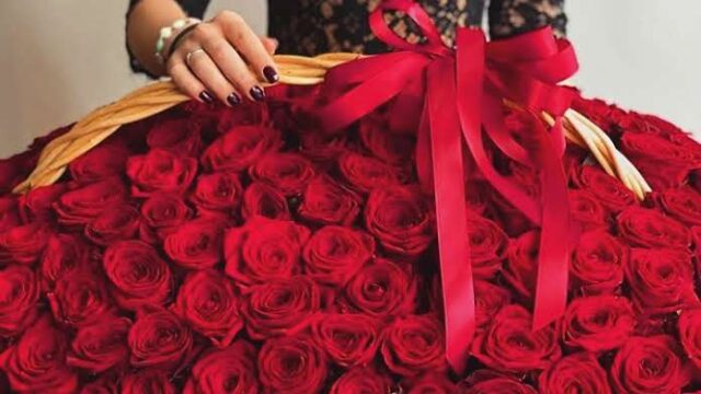 a woman holding a large basket of roses