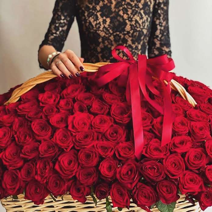 a woman holding a large basket of roses