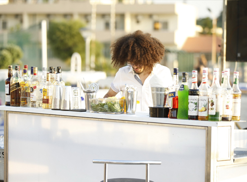 A man standing at a bar, wearing "Le Tablier D'elie".