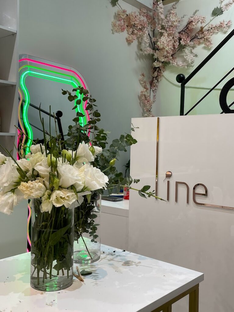 There is a vase of flowers on a table for Line events by Tima.