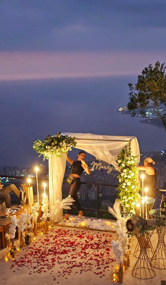 A woman standing on a balcony adorned with a white canopy, flowers, and candles, creating a picturesque scene for Line events by Tima.