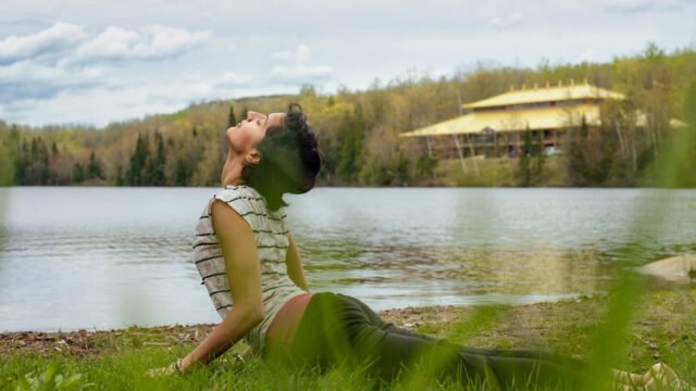 a woman stretching on grass by a lake