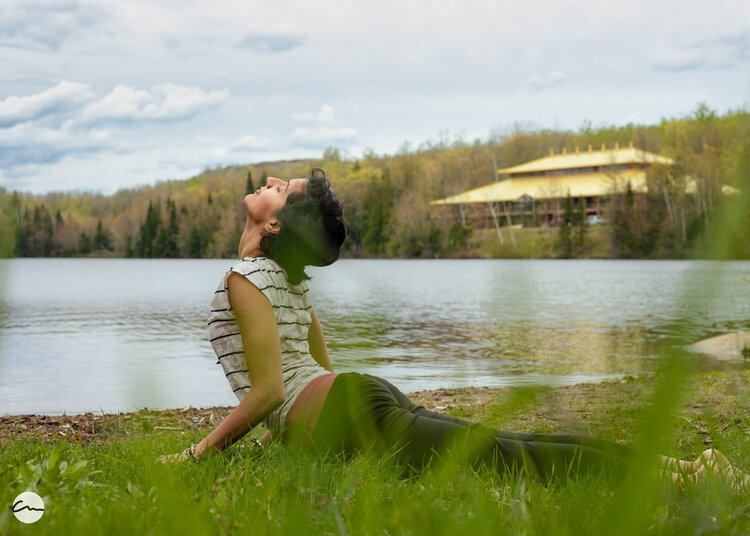 a woman stretching on grass by a lake