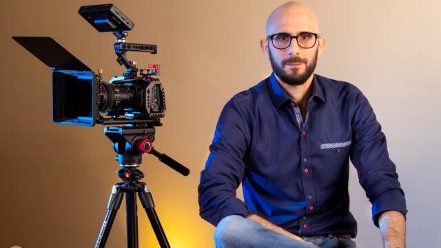 a man sitting next to a camera