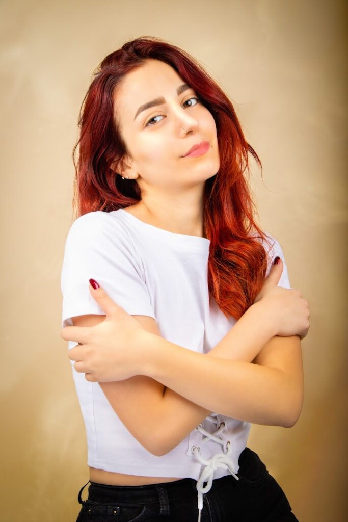 a woman with red hair and white shirt with arms crossed