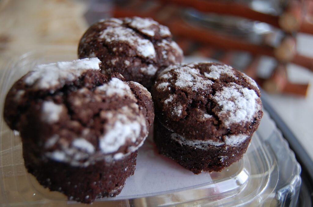 A group of chocolate muffins on a clear plastic plate, My Oasis.