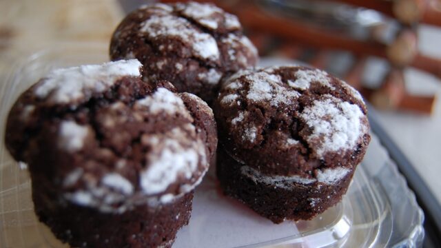 A group of chocolate muffins on a clear plastic plate, My Oasis.