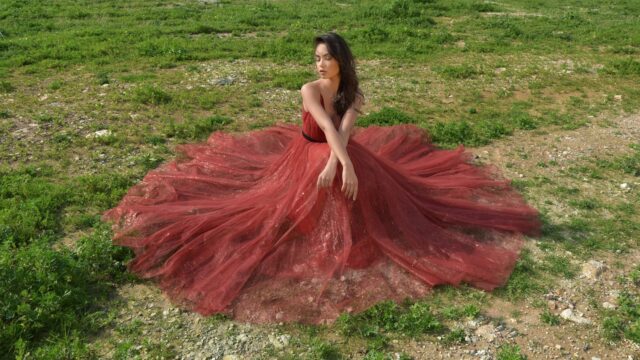 a woman in a red dress sitting on grass