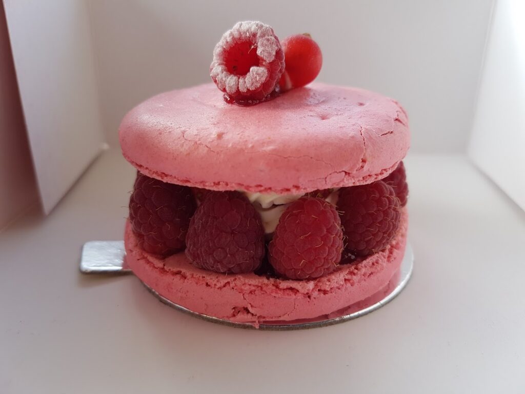 a pink dessert with raspberries and cream offered by Nicolas Audi Catering SAL.