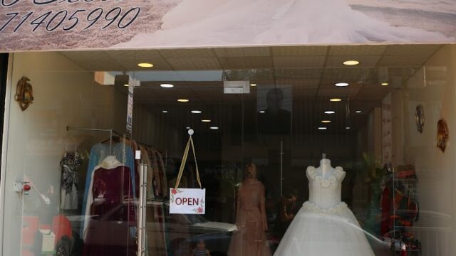 a store front with a sign and a dress on it
