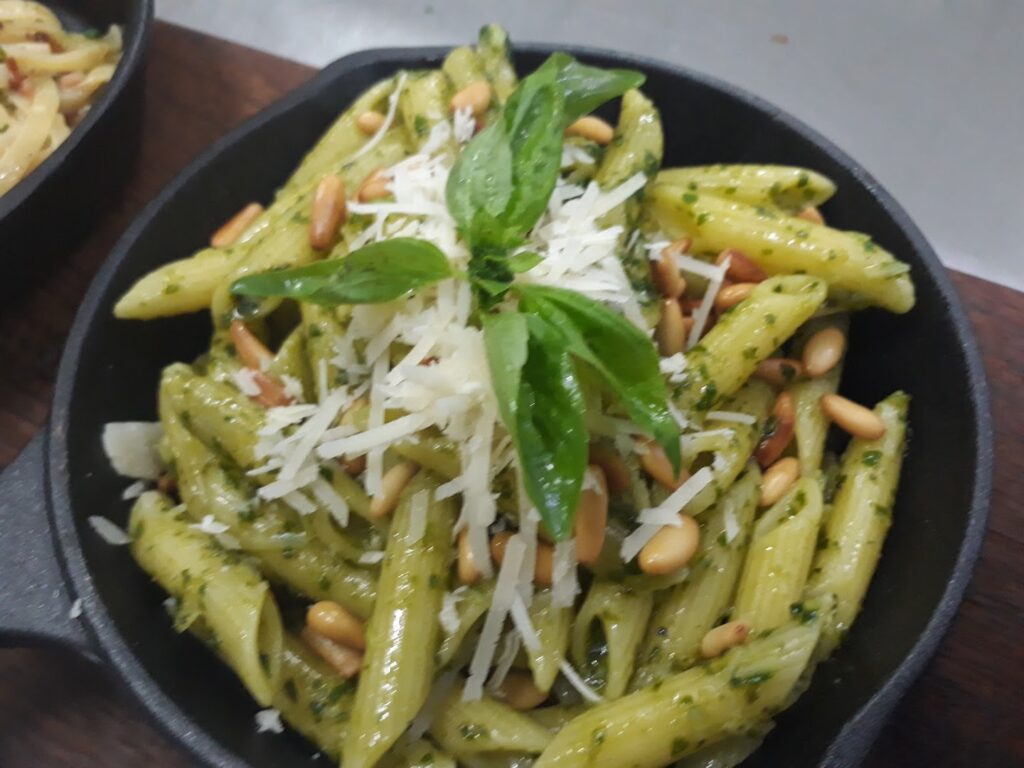 A plate of pasta with basil and pine nuts, served by Saveur Plus Catering.