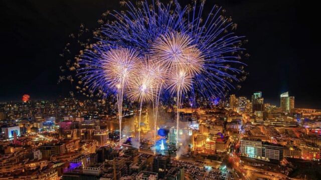 "TABBARA FIREWORKS CO. presents magnificent fireworks in the sky over a city."