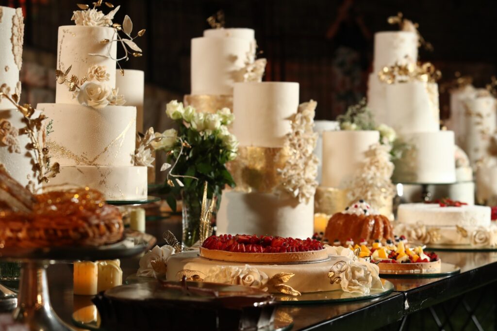 A table with many cakes and flowers from The Catering Boutique.