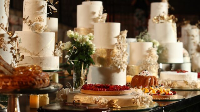 A table with many cakes and flowers from The Catering Boutique.