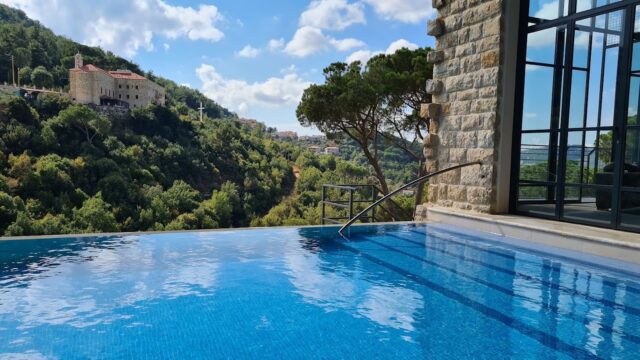 a pool with a stone building and trees in the background