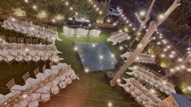 a group of tables and chairs in a yard with lights