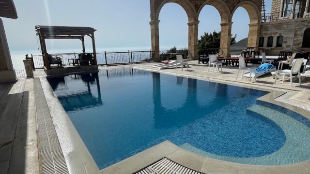 a pool with a stone arch and a building