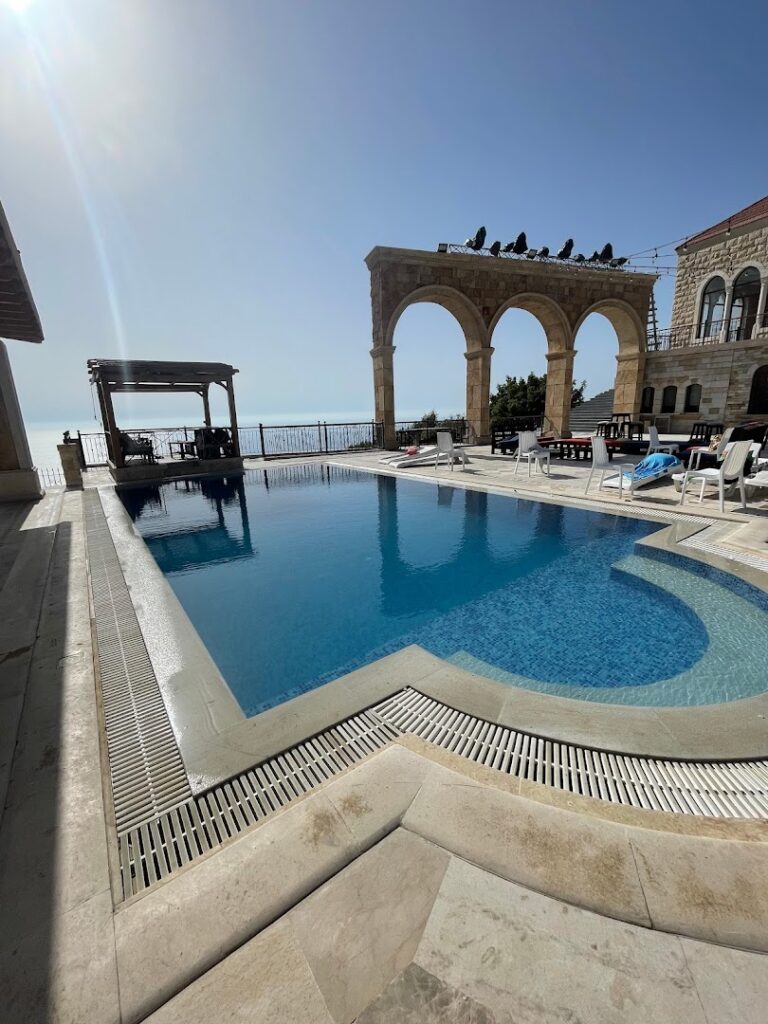 a pool with a stone arch and a building