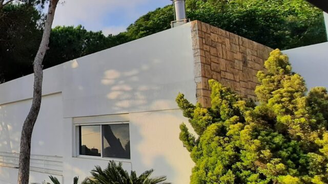 a white building with trees and a metal railing