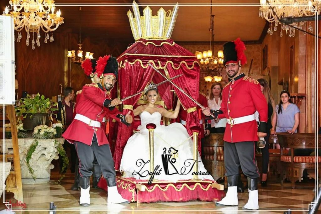 a woman in a white dress with a crown and a couple men in red uniforms