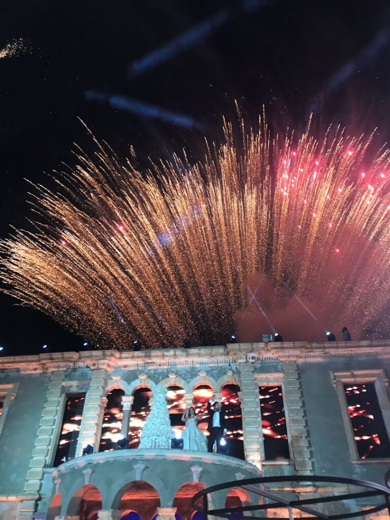 "Adel Eid FireWorks lighting up the sky over a building."