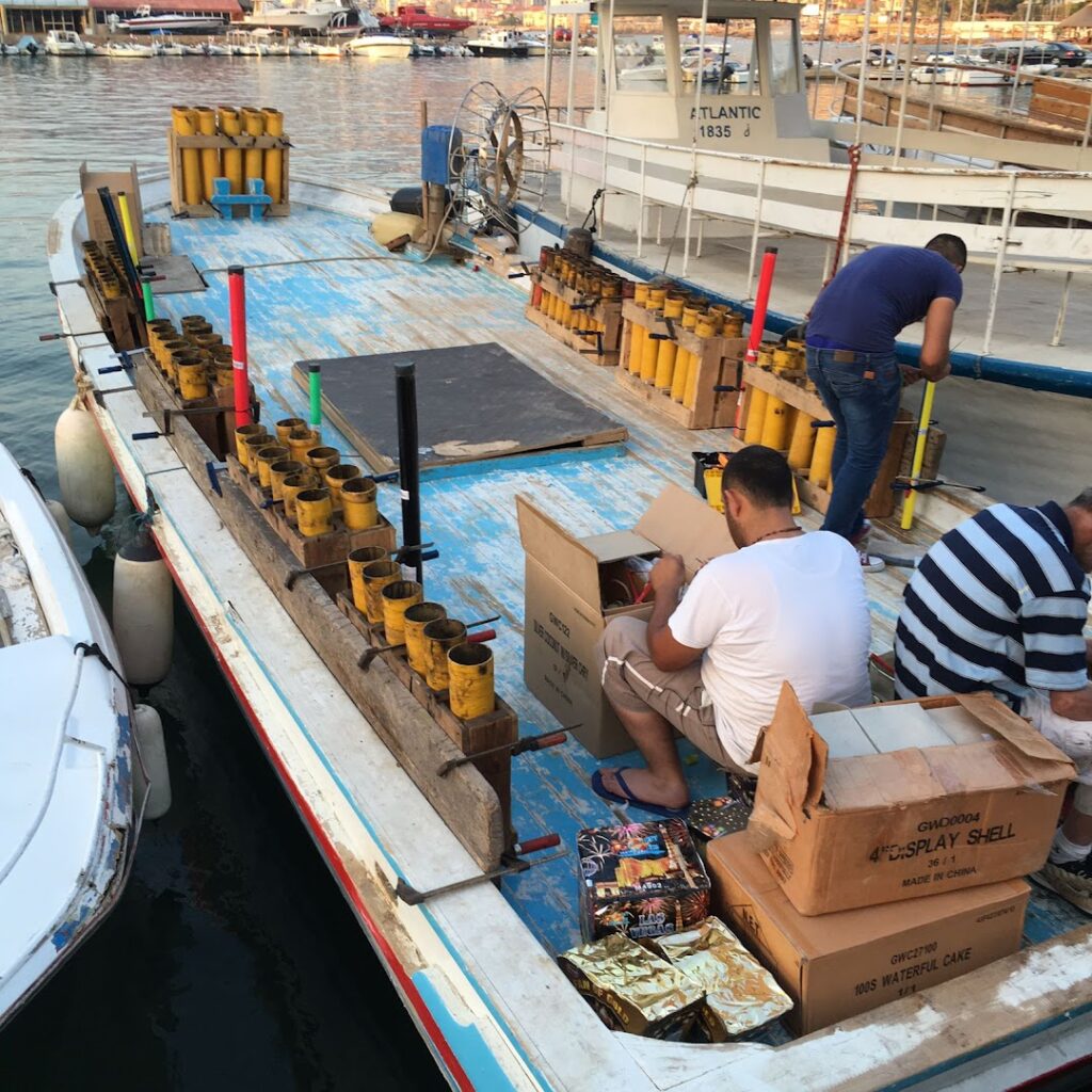 A group of men sitting on a boat, enjoying Adel Eid FireWorks.