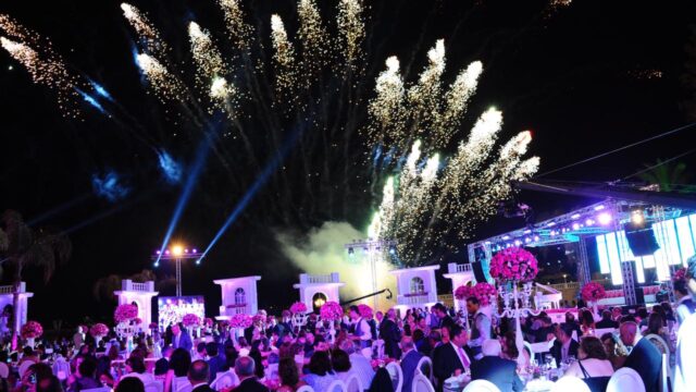 A group of people sitting at tables with Sky Fireworks - Events lighting up the sky.