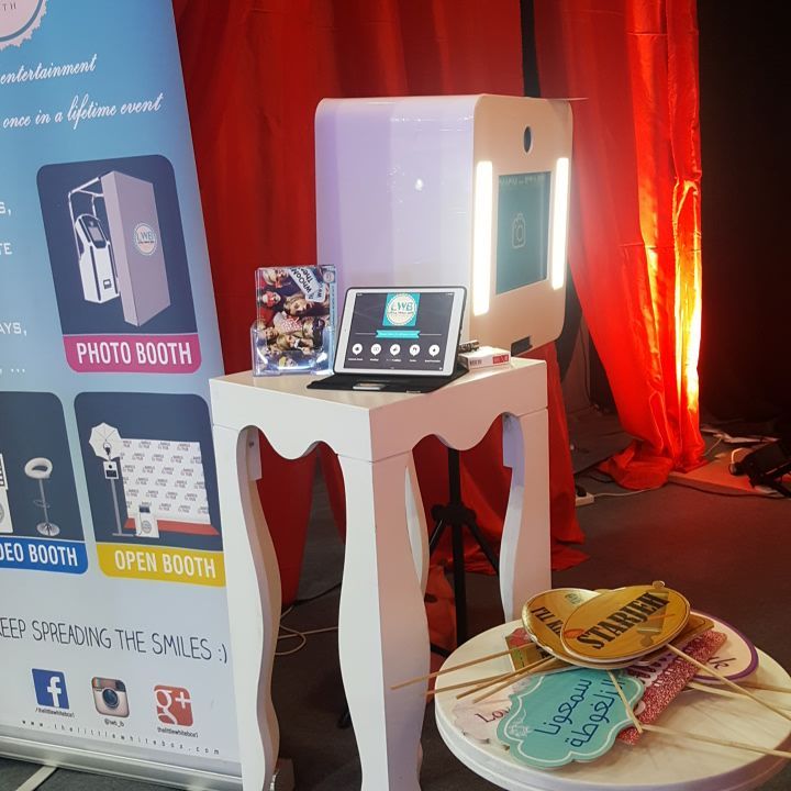 A booth with a laptop, a table, and "The Little White Box."